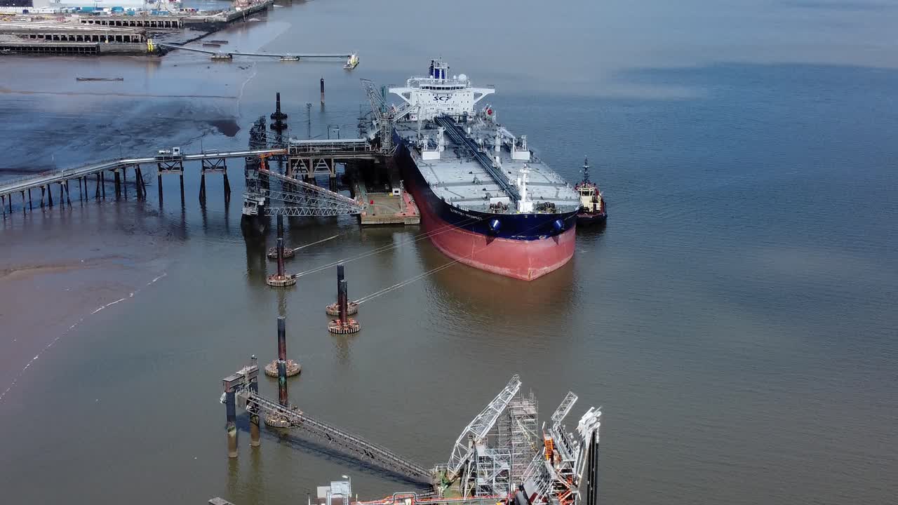 Crude oil tanker ship loading at refinery harbour terminal aerial view reverse above platform