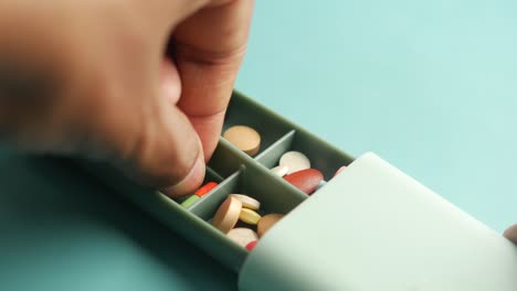 green pill box filled with different medications on a blue table