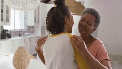 African-american-mother-and-daughter-hugging-each-other-in-the-kitchen-at-home