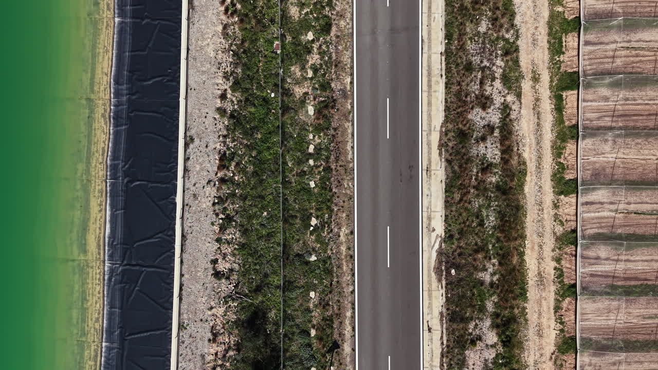 Strada che costeggia un corso d'acqua e campi vicino a un'area agricola durante le ore diurne, mostrando vari usi del suolo e le texture della natura