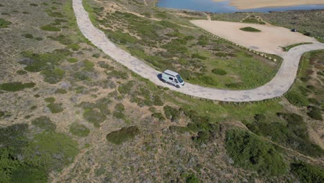 aerial tracking shot of a camper van arriving at bordeiras beach on the coast of algarve portugal at sunset