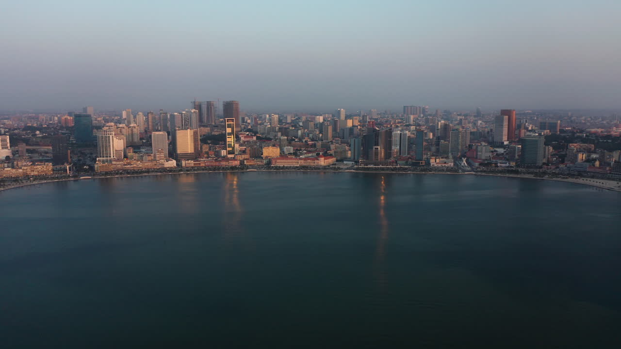 Avanzamento rapido, skyline della città di Luanda, ora d'oro, sorvolo della baia di Luanda, Africa.