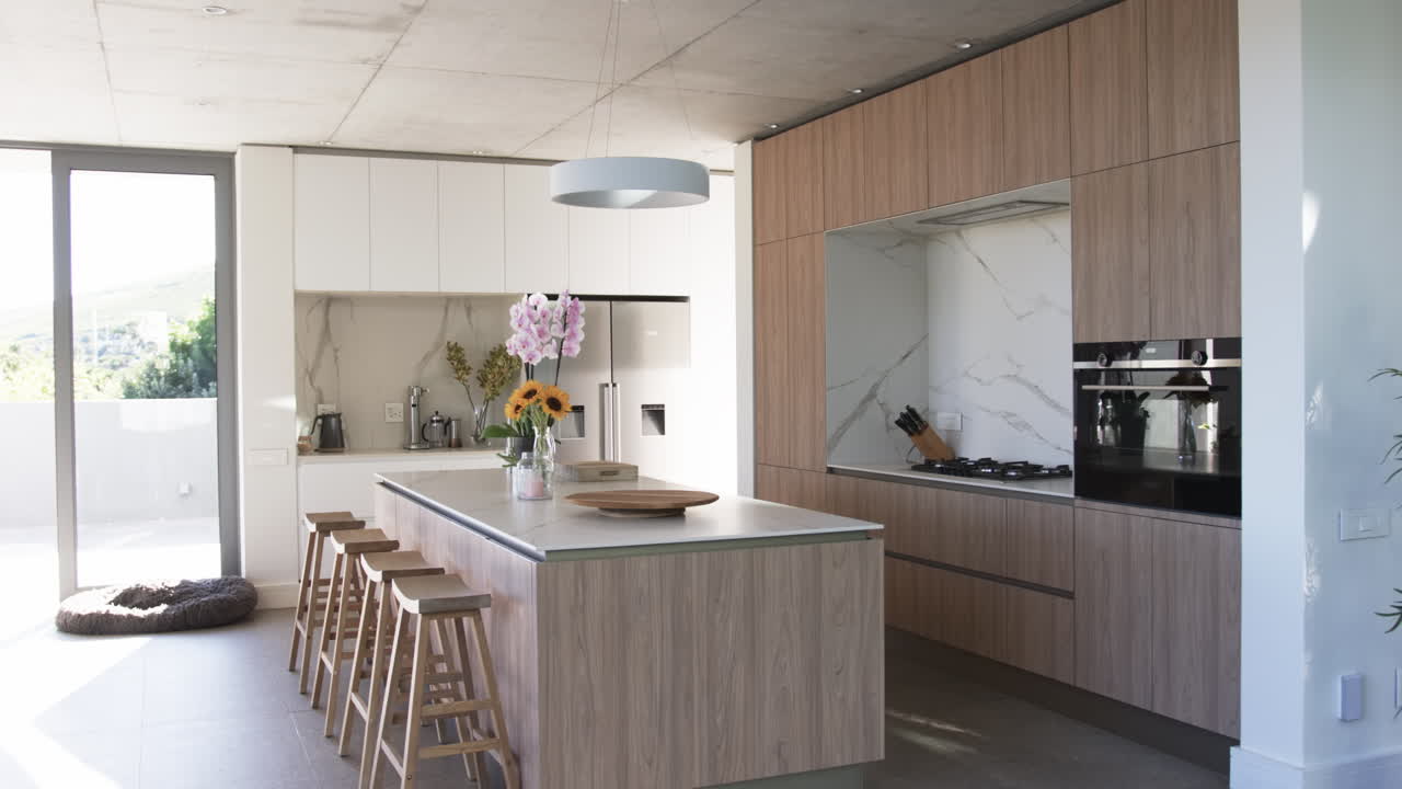 Uma cozinha moderna apresenta armários com acabamento em madeira e uma ilha central com bancos de bar.