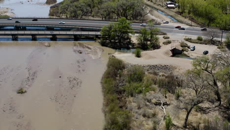 bridge with cars and traffic crossing rio grande river in new mexico - drone