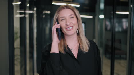 Empresaria-Sonriente-Mirando-Por-Teléfono-Celular-En-El-Interior.-Mujer-De-Negocios-Sorprendida-Leyendo-Un-Mensaje-En-Un-Teléfono-Móvil-En-El-Pasillo-De-La-Oficina.-Mujer-Mirando-La-Pantalla-Del-Teléfono-Inteligente-En-El-Centro-De-Negocios.-Oficina-Para-Caminar