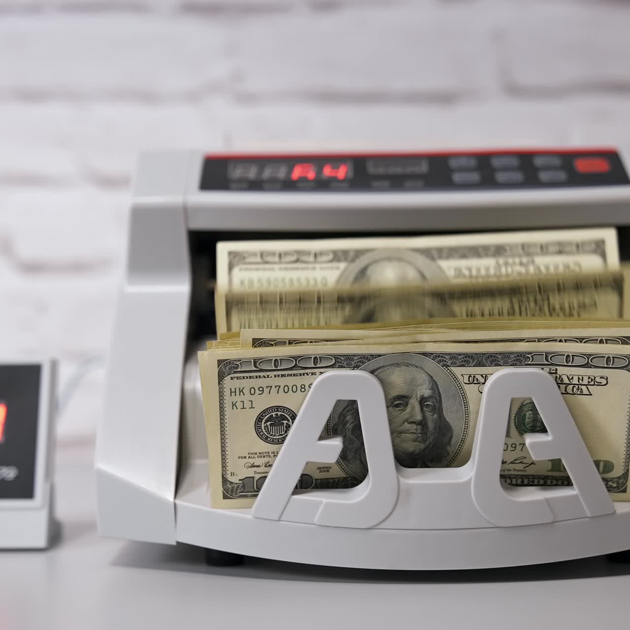 Electronic cash counting machine. Bank financial operations and calculating dollar banknotes. Female hand puts paper money into automatic equipment for counting bills