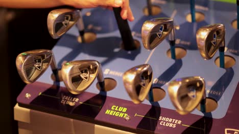 hands choosing golf clubs from a display