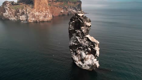 drone footage of a single cliff that rises from the ocean in north iceland