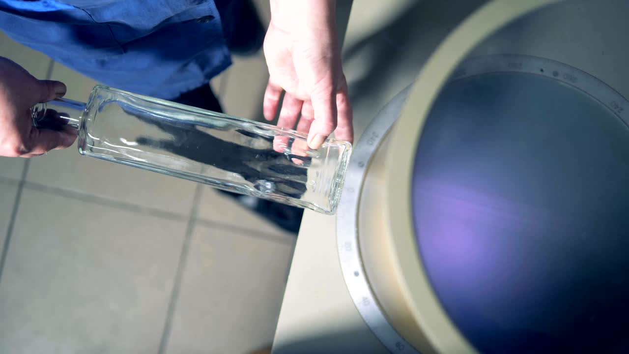 trabajador inspecciona una botella, vista de arriba.