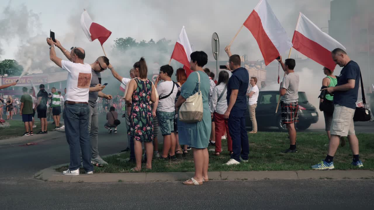People Waving Polish Flags at a Gathering with Smoke