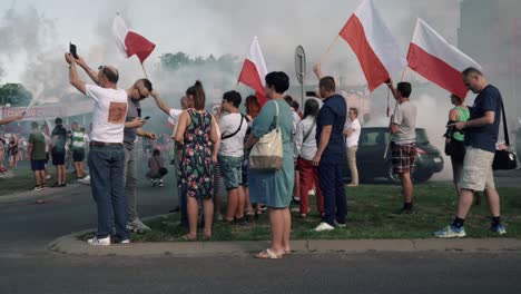 people waving polish flags at a gathering with smoke