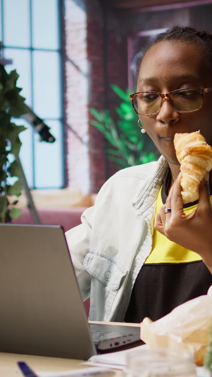 Vertical video Busy freelancer in home office eating snack on the go while typing on laptop