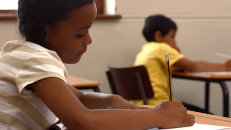 Escolar-Escribiendo-En-El-Bloc-De-Notas-En-La-Escuela