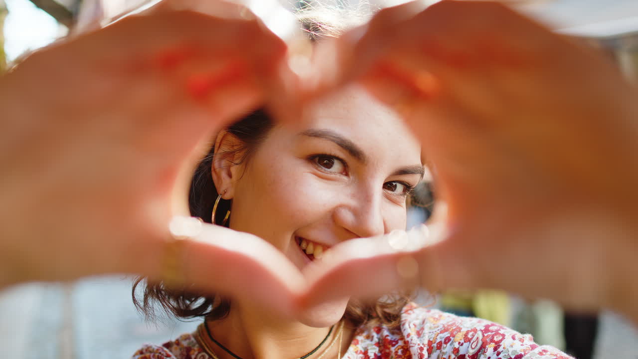 Young woman makes symbol of love showing heart sign to camera express romantic positive feelings