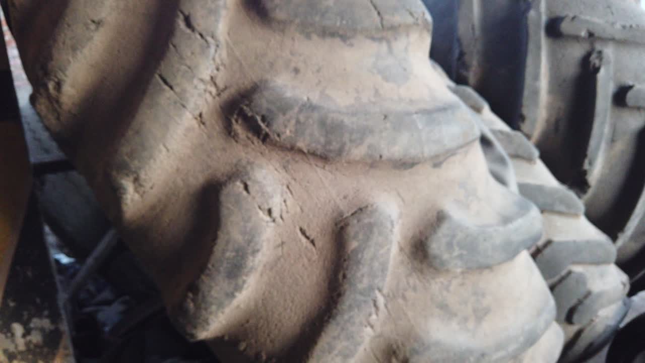 Closeup shot of giant tires for the wheel, old used dusty field tractors