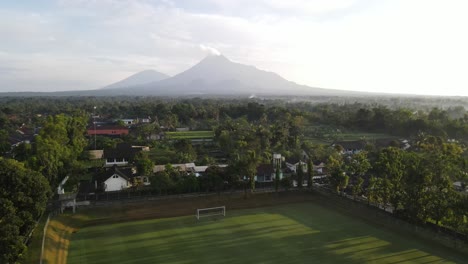 aerial footage using drones. purwobinangun sports or soccer field in yogyakarta with a beautiful background of mount merapi. recorded in the morning.