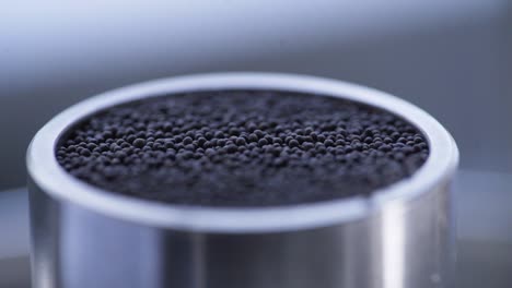 pouring dark granules into metal container