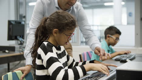 schoolgirl and male teacher working together on computer