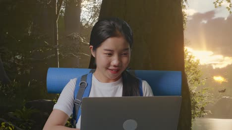 close up of asian female hiker with mountaineering backpack looking at a laptop and saying wow while exploring forest nature