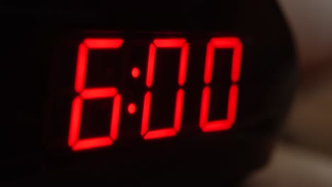 Close-up of black digital clock screen showing 6.00. Blinking red digital numbers on black background. Modern timer system and neon light, electric alarm device
