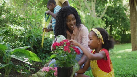 Animation-of-happy-african-american-mother-and-daughter-planting-flowers-in-garden