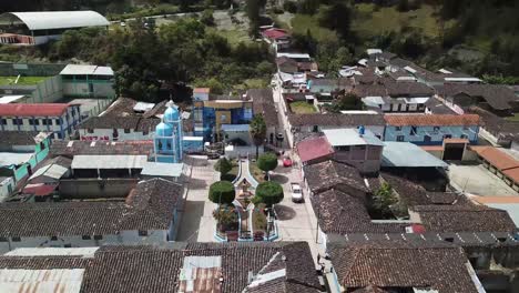 beautiful aerial shot of the main square of huasmin, cajamrca, peru. the image highlights colonial-style rooftops, a vibrant blue church, and a picturesque plaza adorned with greenery.