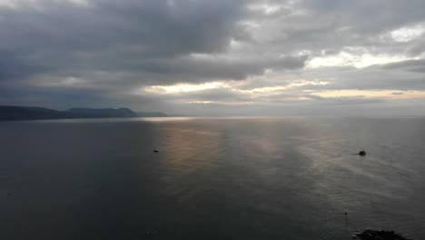 Aerial-shot-looking-over-the-sea-and-coastline-of-the-Jurassic-coast-from-Lyme-Regis-England-with-a-dramatic-early-morning-sunrise