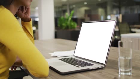 mujer de negocios biracial que usa una computadora portátil para una videollamada con espacio para copiar