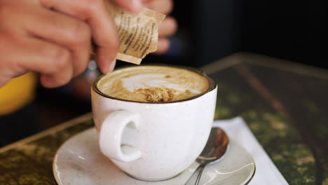 mujer poniendo azúcar marrón en el café