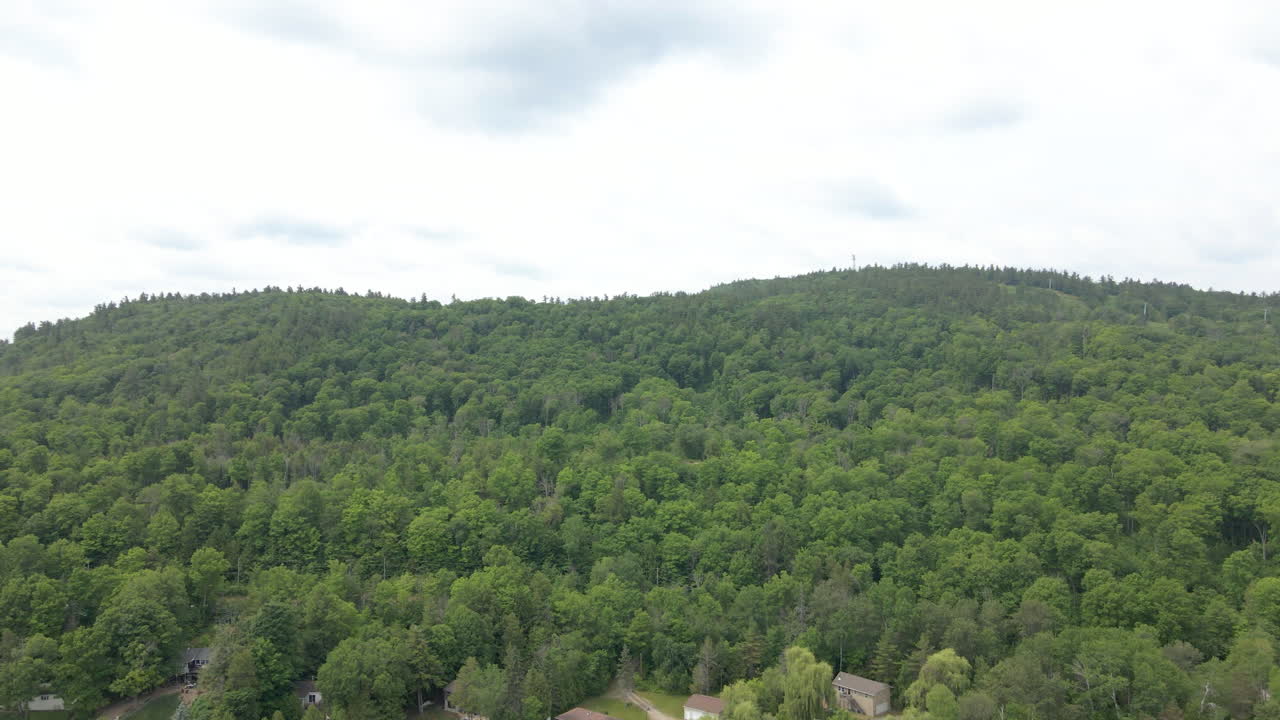 Aerial shot from lake rising over thick forest covered mountain. Calabogie Ontario