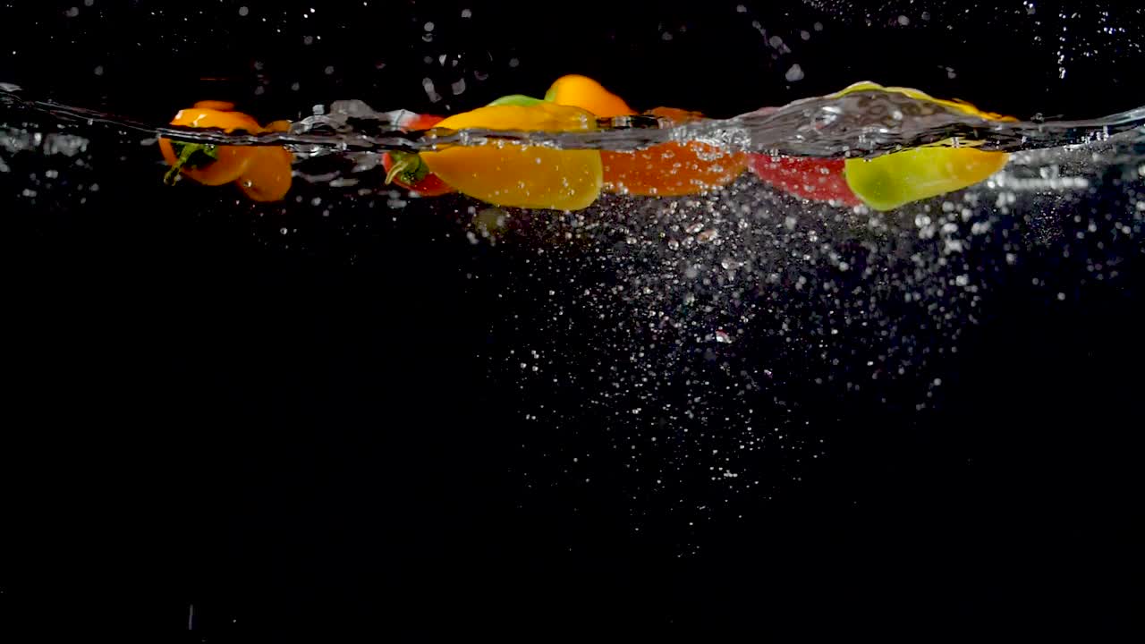 느린 동작으로 물에 떨어지는 다채로운 달콤한 고추