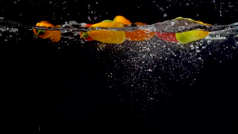 colorful sweet peppers being dropped into water in slow motion