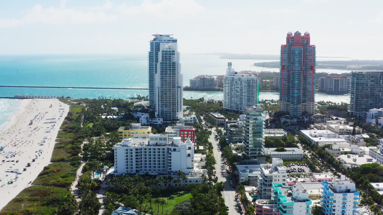 A sweeping drone fly right captures Miami’s South Beach skyline alongside the shimmering turquoise shoreline under bright sun.