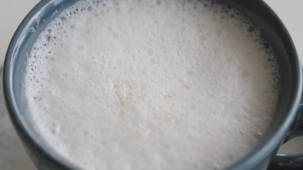 A cup of frothy coffee drink with sugar