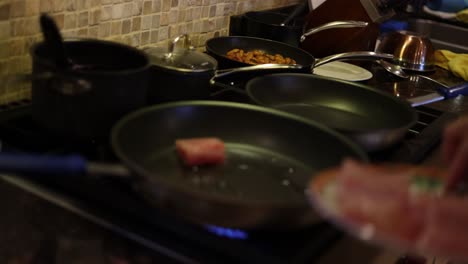 chef pan frying fish filets on kitchen stovetop