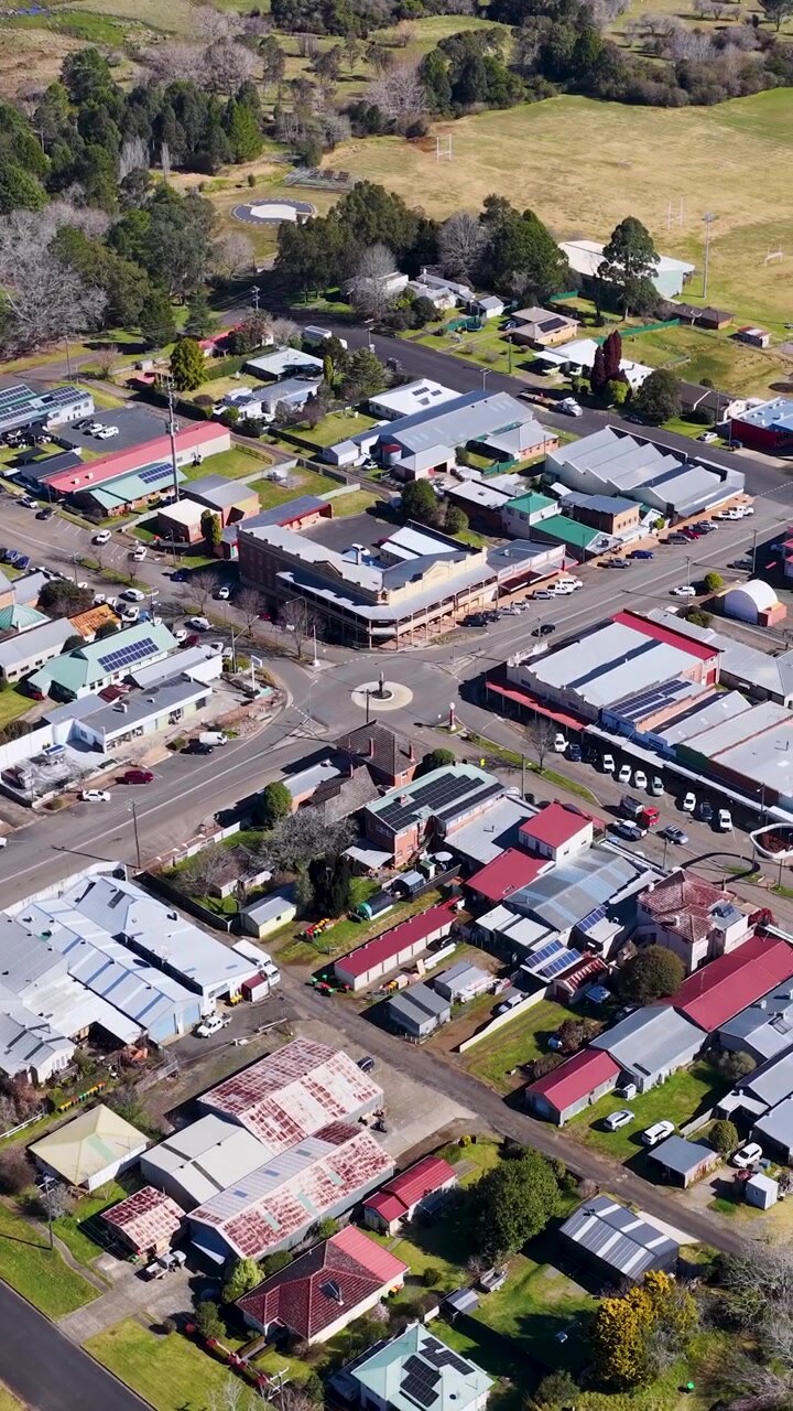 Un drone si alza sopra Dorrigo, rivelando il centro rurale della città, negozi, strade e il paesaggio circostante alla luce del giorno