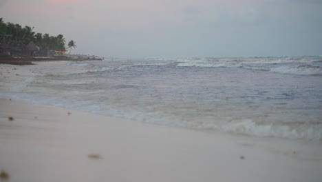 small waves rolling and breaking on beach shore during grey evening twilight after sunset