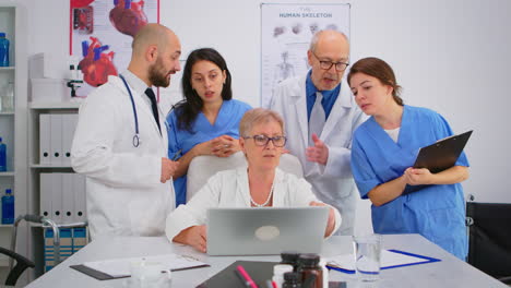 médicos en abrigos de laboratorio trabajando en la oficina del hospital discutiendo síntomas de la enfermedad