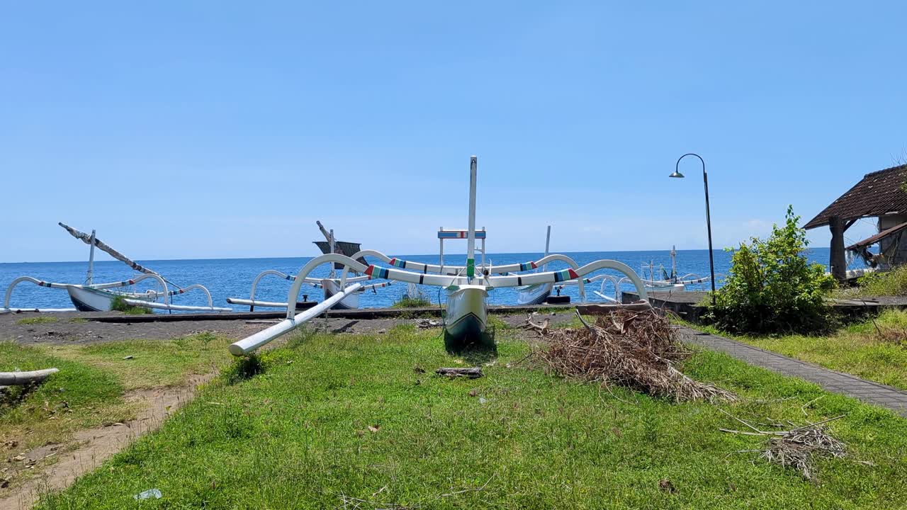 Local traditional fishing and tourism outrigger boat on coastline at Amed on tropical island of Bali Indonesia