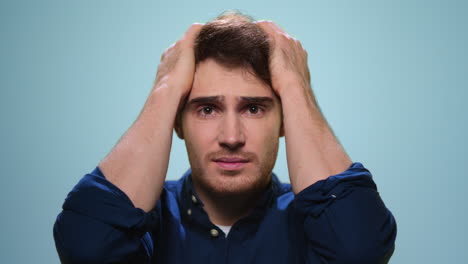 Stressed-man-touching-head-with-hands-in-studio.-Male-student-having-stress