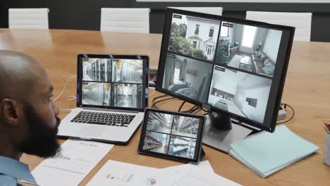 African-american-male-security-officer-watching-cctv-camera-views-on-three-screens,-slow-motion