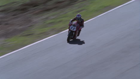 a motorcycle rider speeds out of a sharp turn into a straight away