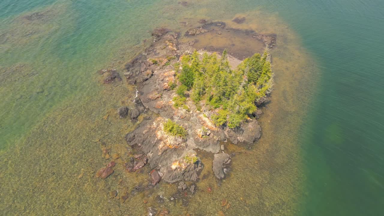 Aerial View of a Small Rocky Island with Trees in Clear Water