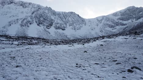 Aerial-drone-footage-revealing-Stob-Coire-an-t-Sneachda-and-a-boulder-field-at-its-base-in-the-Cairngorm-mountains-of-Scotland-in-snow,-ice-and-full-winter-mountaineering-conditions