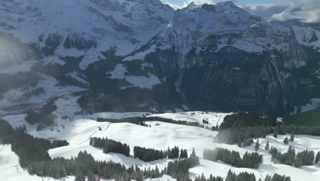 Aerial-drone-zoom-in-shot-over-chairlifts-going-up-the-mountain-at-Engelberg-Brunni-bahnen-along-the-Swiss-alps-in-Switzerland-on-a-cold-winter-day