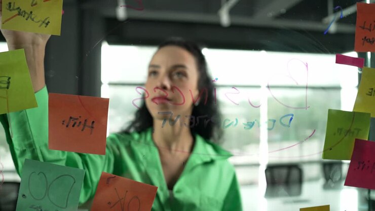 Una brillante donna d'affari ispanica scrive idee di marketing su una lavagna di vetro.