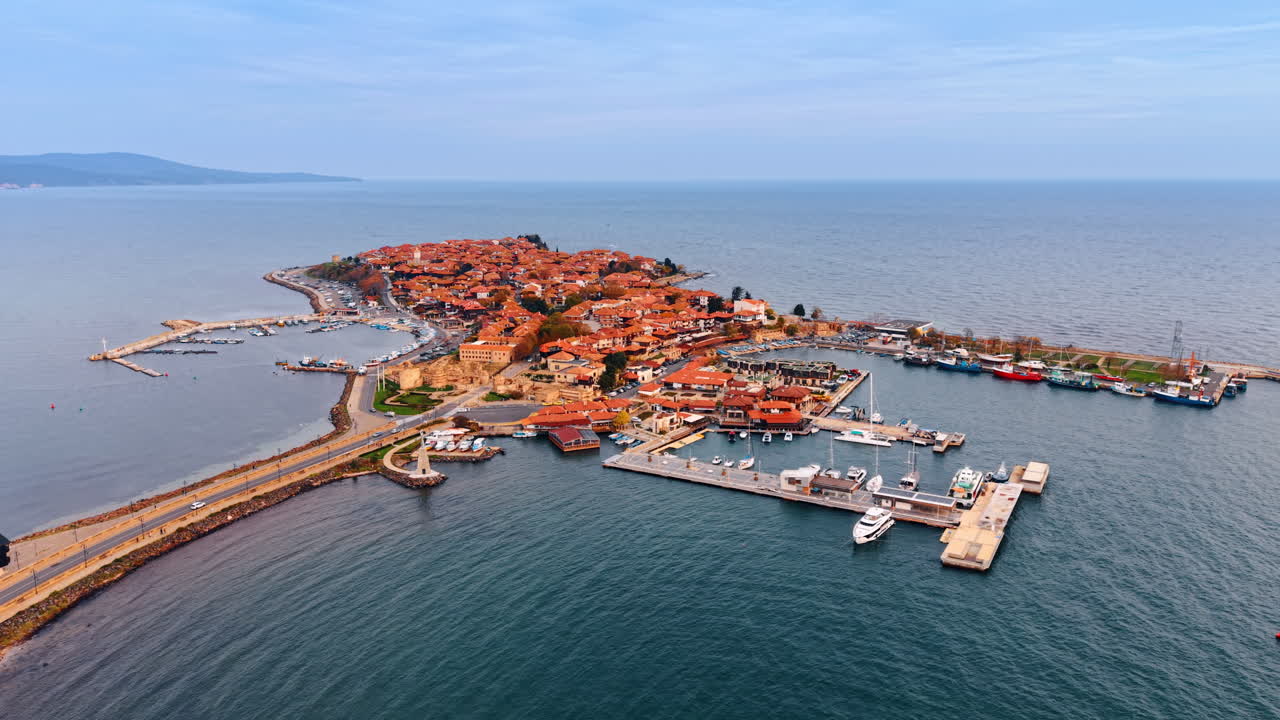 Flygbild över Nessebars gamla stadsdelshalvö i Bulgarien. Vidvinkelbild i högt perspektiv av den historiska halvön med terrakottafärgade tak, omgiven av Svarta havet under en klar himmel