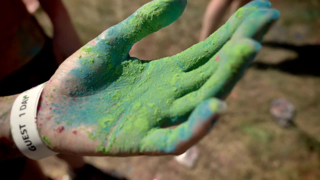 Someone shows hand in colorful powder on holi festival in daytime in summer, color concept