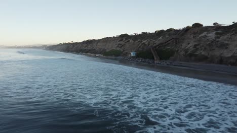 A-beautiful-aerial-drone-shot,-flying-along-the-coast-during-golden-hour,-Carlsbad-State-Beach---California