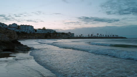 twilight beach drone shot on low tide waves reflecting wide sky during sunset